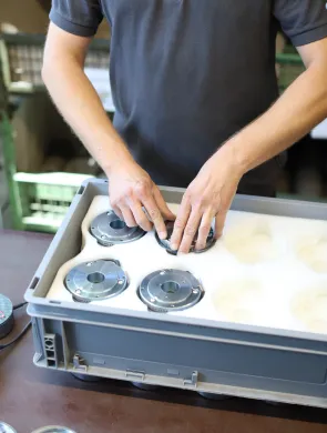 Mitarbeiter platziert Bremsen in einer Kunststoff-Box mit Schaumstoff, samt entsprechenden Aussparungen für Bremsen