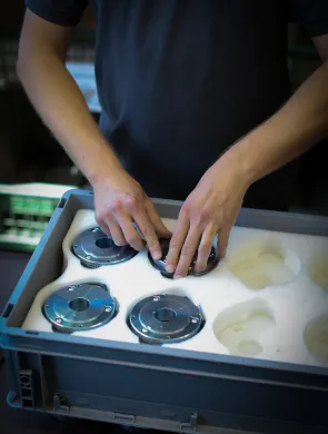 Mitarbeiter platziert Bremsen in einer Kunststoff-Box mit Schaumstoff, samt entsprechenden Aussparungen für Bremsen