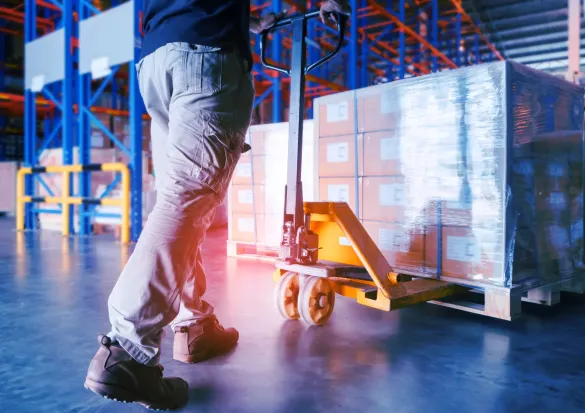 Mitarbeiter bewegt beladene Palette mit einem Hubwagen